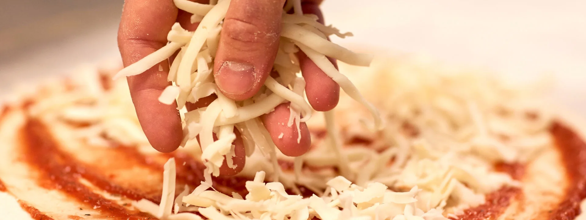 Τυρί τριμμένο Alpiland που απλώνεται σε πίτσα